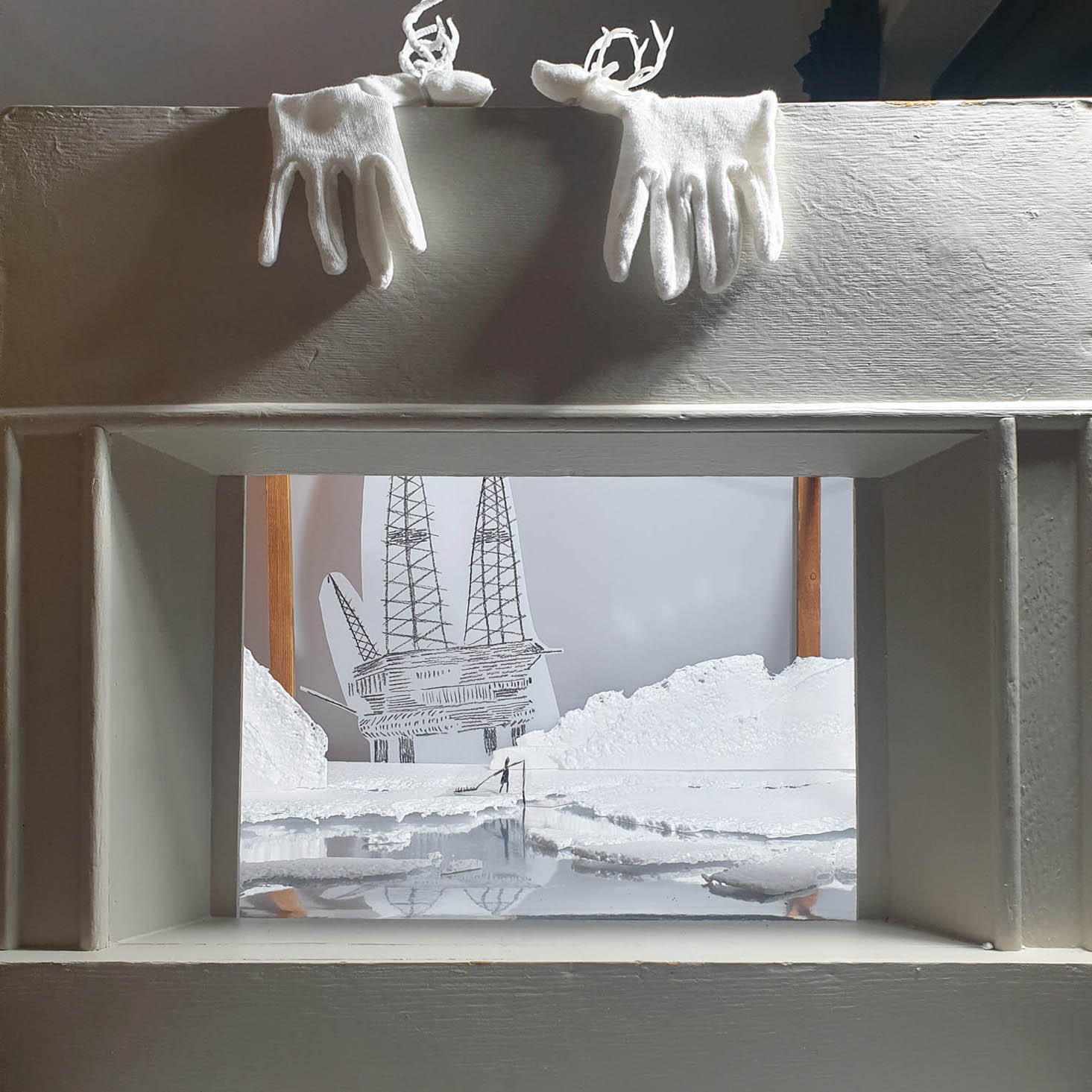 vintage model theatre with white gloves made to look like reindeer on the top and artic scenes inside made of polystyrene packaging, silver card and drawings